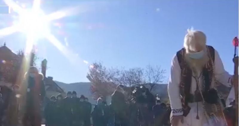 Un bătrân în costum popular, cu mască de protecție și-n baston și-a luat rămas bun