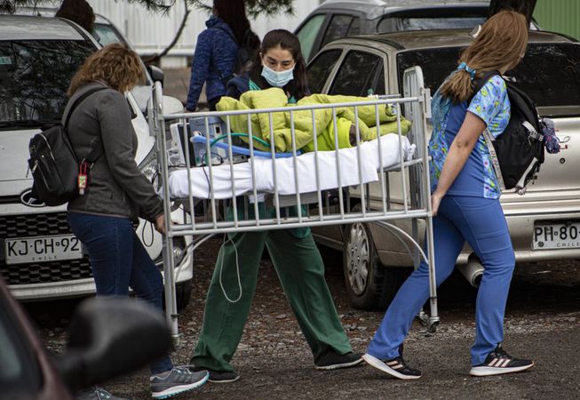 O asistentă și un civil cară patul unui bolnav 
