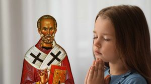 O fetiță se roagă la Sfântul Nicolae