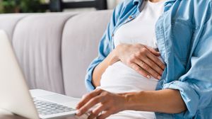 Tânără însărcinată, folosind un laptop