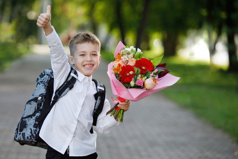 Elev cu un buchet de flori, în drum spre școală