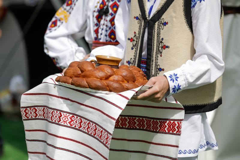 Tineri, în costume tradiționale, pâine pe o tavă
