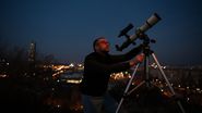 Bărbat, studiază luna, cu ajutorul unui telescop