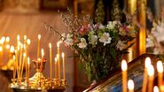 Lumânări aprinse și flori în biserică