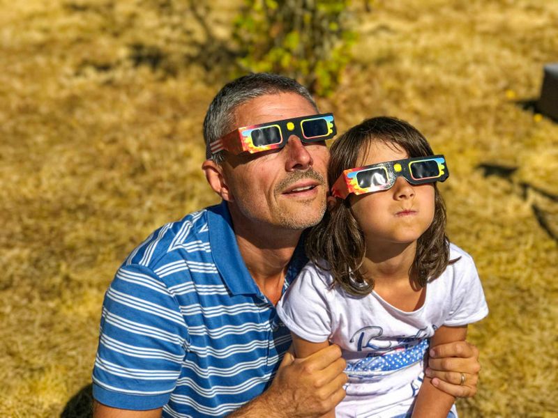 Două persoane care privesc eclipsa de soare cu ochelari speciali Eclipsă de soare