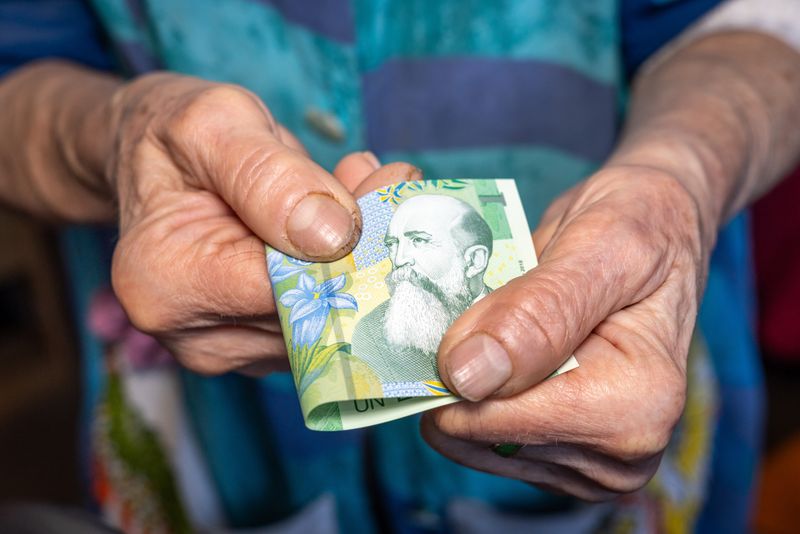 V&acirc;rstnică, țin&acirc;nd &icirc;n m&acirc;nă o bancnotă de 1 leu