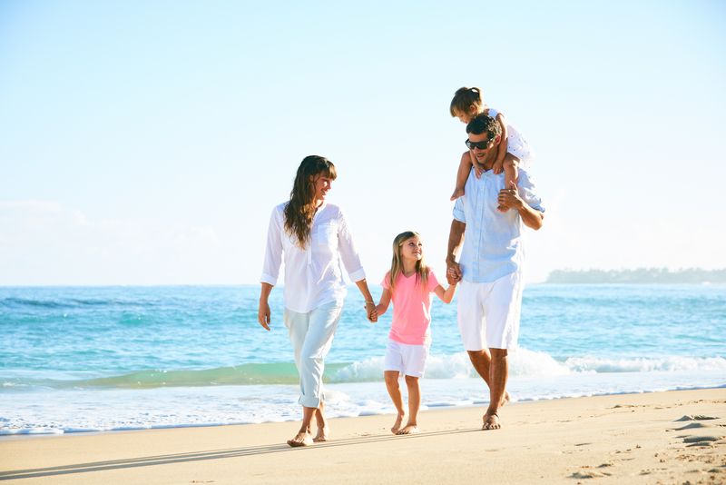 Familie cu doi copii, se bucură de plimbare pe plajă