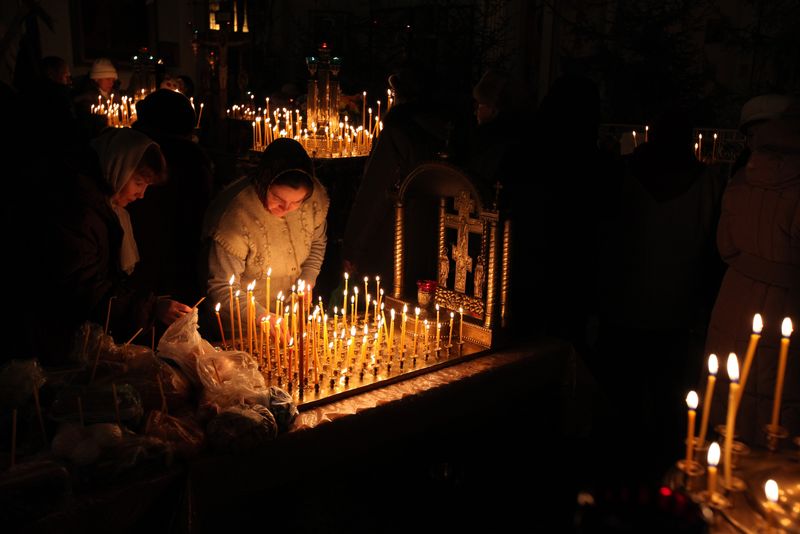 Credincioși, aprind lumânări în biserică