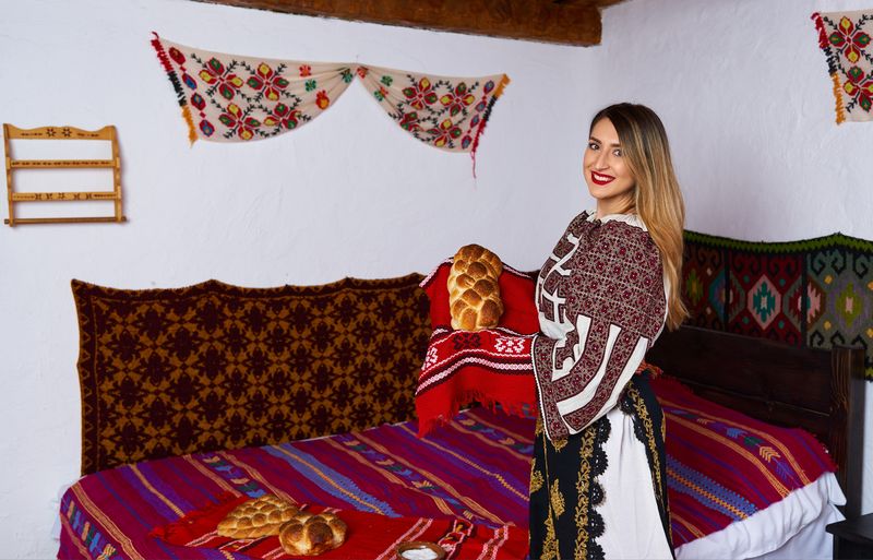 Tânără îmbrăcată în costum tradițional, pâine proaspătă