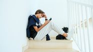 tanar pe scari cu ochii in telefon
