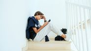 tanar pe scari cu ochii in telefon