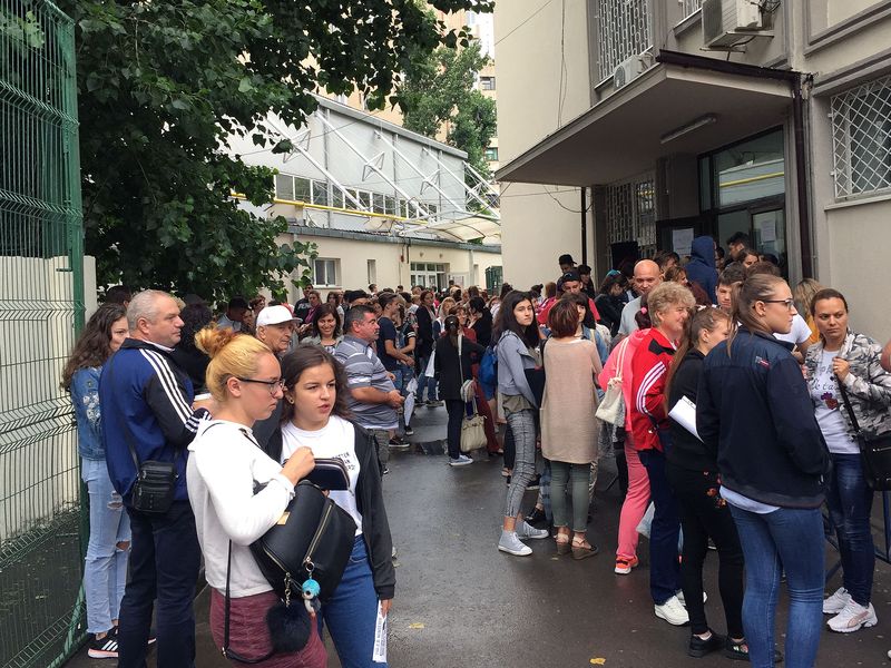 Elevi și părinți care privesc tabelul cu rezultatele de la Evaluarea Națională