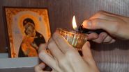 mana care aprinde o candela la icoana maicii domnului