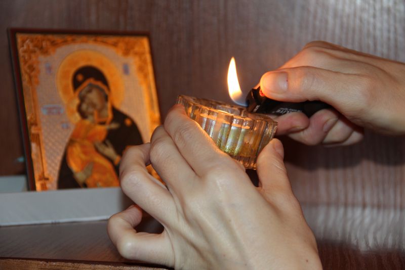 mana care aprinde o candela la icoana maicii domnului