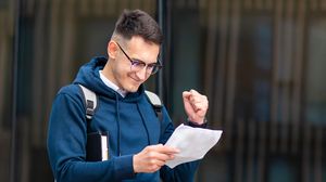 Elev mulțumit de rezultatul obținut  elev cu foaie in mana, se bucura