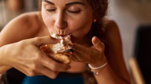 Femeie care se bucură de mâncare  femeie care musca dintr o felie de pizza