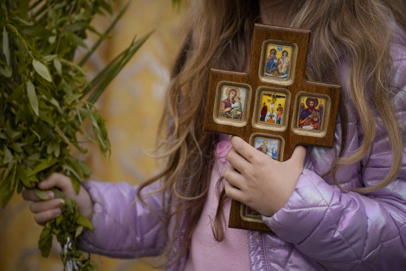 Fetiță cu crucea &icirc;n m&acirc;nuță