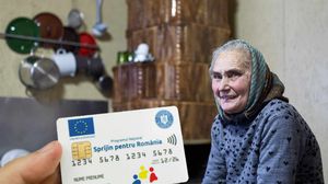 Card cu tichete sociale și o femeie lângă sobă