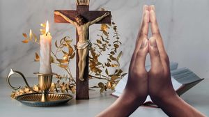 Rugăciune, cruce și lumânare aprinsă pe masă