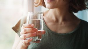 Tânără, ține în mână un pahar cu apă