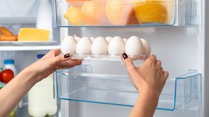 Tânără, așează ouă pe ușa frigiderului
