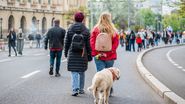 Oameni, se plimbă pe Calea Victoriei, cu un cățel