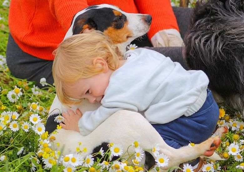 copil care imbratiseaza un caine