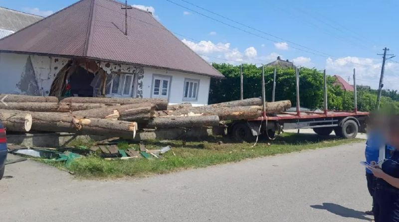 Încărcătura de lemn s-a rostogolit peste gardurile a două gospodării, distrugând colțul unei case.