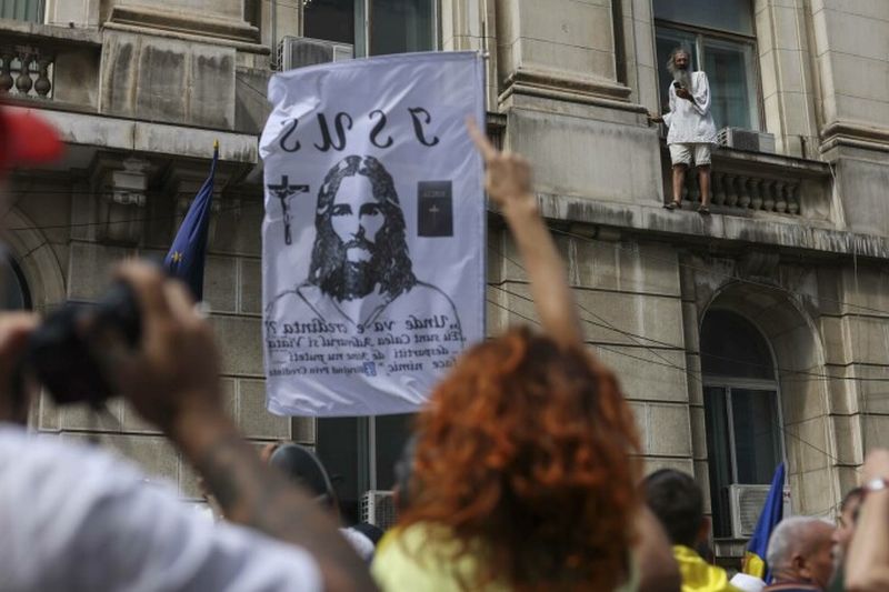 Un bărbat s-a urcat pe clădire fluturând drapelul României.