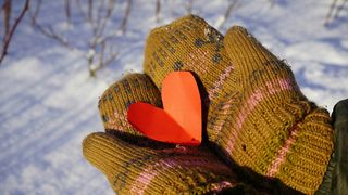 maini care tin o inima rosie de hartie iarna