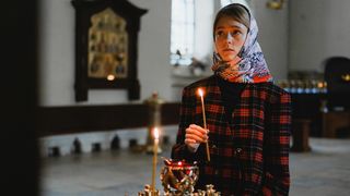 femeie care aprinde o lumanare in biserica