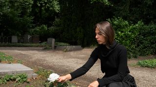 femeie care pune flori la mormant