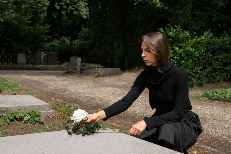femeie care pune flori la mormant