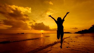 femeie fericita care zburda pe plaja