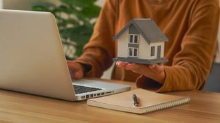 femeie cu laptop si o ccasa in miniatura