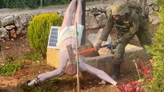 Un soldat israelian distruge cu ciocanul statuia lui Iisus Hristos