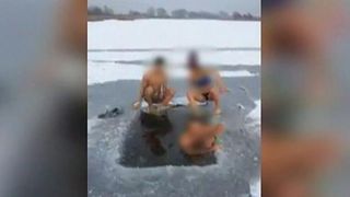 Doi tineri sar in copca adanca de un metru de pe un lac inghetat. Sport extrem in apa rece, inainte de Boboteaza