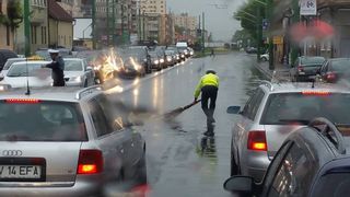 Respect! Un politist din Brasov, fotografiat in timp ce matura carosabilul, pe ploaie, dupa un accident
