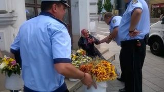 Fotografia care a starnit un val de revolta pe internet. O batranica este luata pe sus de politistii locali din Cluj pentru ca vindea flori