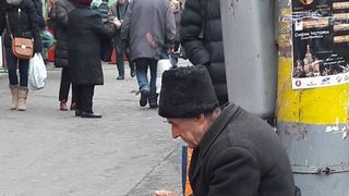 Imaginea care face cat o mie de cuvinte. Un batranel intepenit de frig, incearca sa isi castige banii de o paine, pe o strada din Cluj