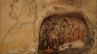 Pe un perete este desenat un chip de barbat si un semn inexplicabil: hexagrama si cercul Yin-Yang