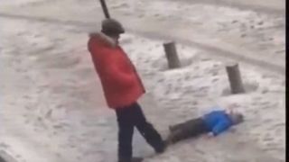 Un barbat isi loveste copilul cu piciorul pentru ca acesta nu isi putea mentine echilibrul pe gheata. Imagini cu un puternic impact emotional!