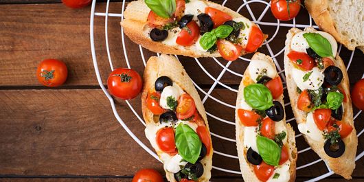 Bruschette cu roșii cherry, mozzarella, măsline și busuioc. Sunt gustoase atât calde, cât și reci, ceea ce le face ideale pentru ieșirile în aer liber!