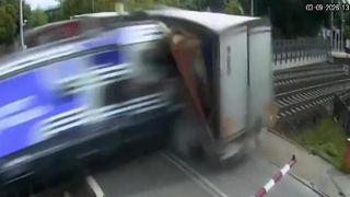 VIDEO Un camion a fost blocat pe șine de bariere, dar șoferul n-a vrut să le spargă și nu a mai reușit să evite trenul